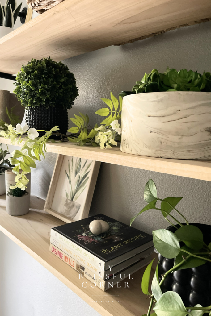 Floating shelf decor featuring layered plants, trailing greenery, and ceramic planters.