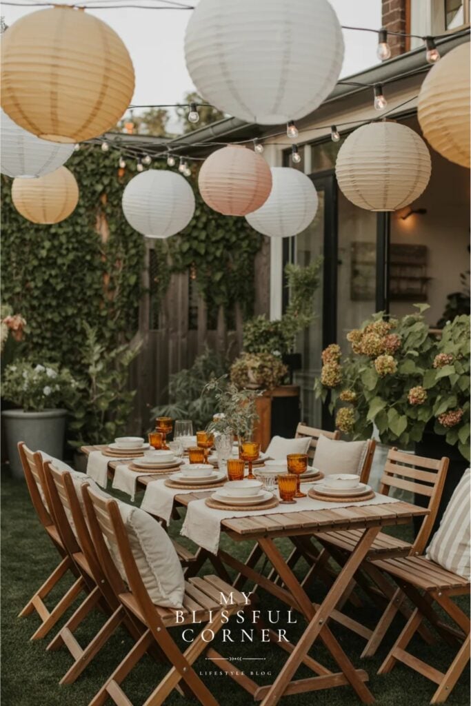 Backyard party aesthetic with paper lanterns, string lights overhead and styled outdoor dining table with folding chairs