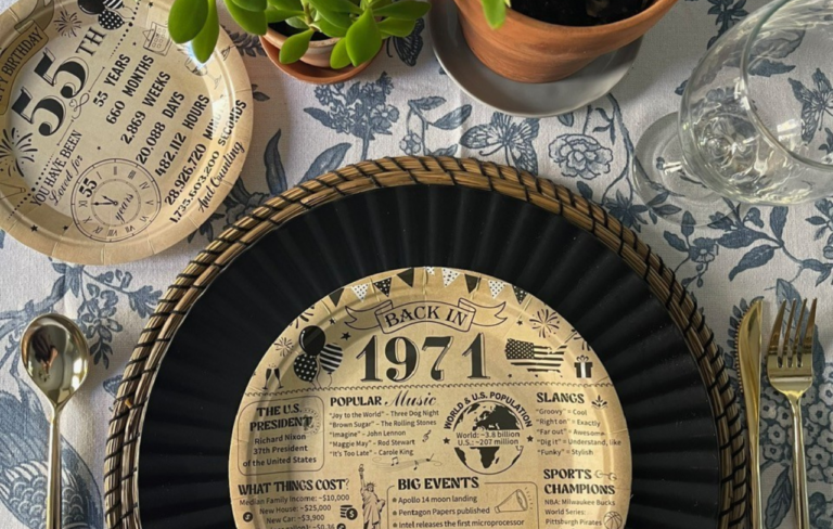 Birthday table set up for men with black charger plates, wicker placemats, and vintage themed disposable plates