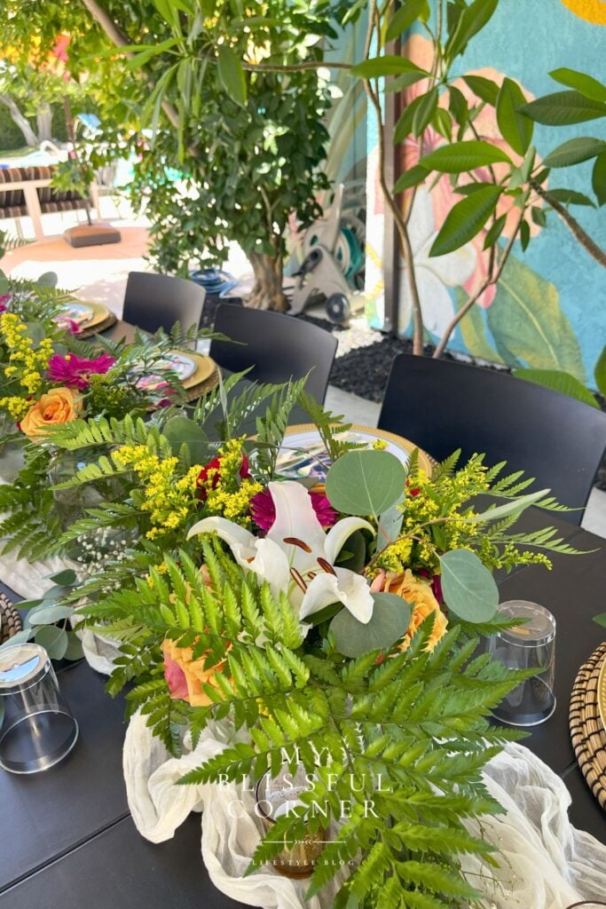 Simple tropical flower arrangement with pink lilies roses fern leaves and greenery