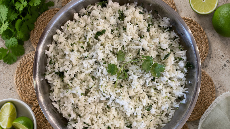 Chipotle cilantro lime rice copycat recipe featuring fluffy jasmine rice, fresh cilantro, and lime wedges in a serving bowl.