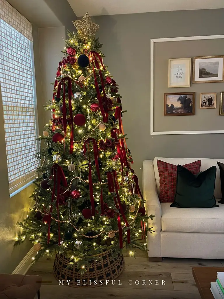Ralph Lauren Christmas tree in a living room with burgundy velvet ribbons, velvet ornaments, and a plaid pillow on the sofa