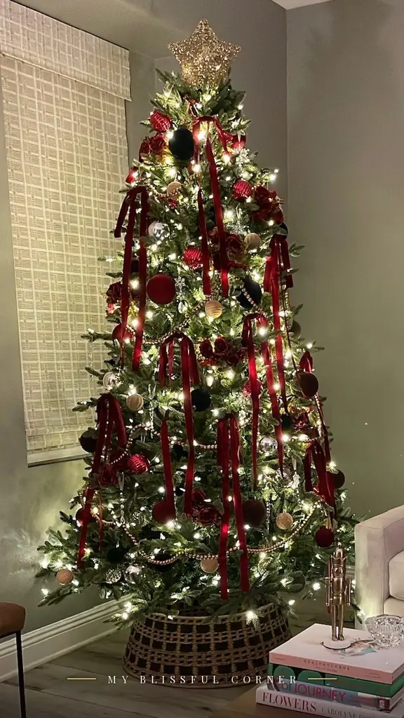 Ralph Lauren Christmas tree with burgundy velvet ribbon streamers, wood bead garland, and gold star topper, lit at night